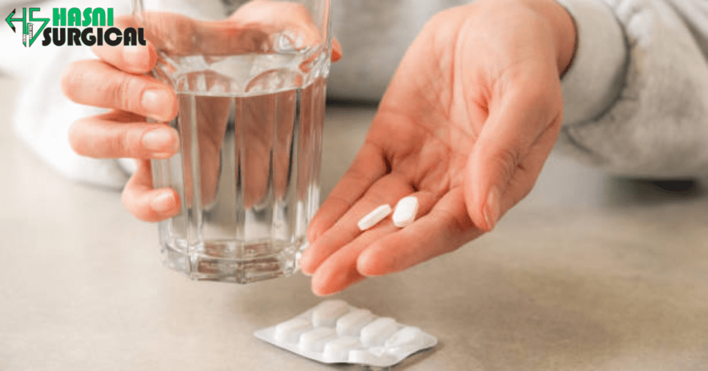 A man taking two pain reliever pills with a glass of water.