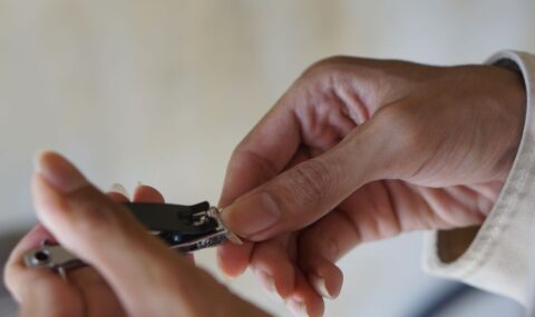 Close-up of hands using nail clipper for personal grooming