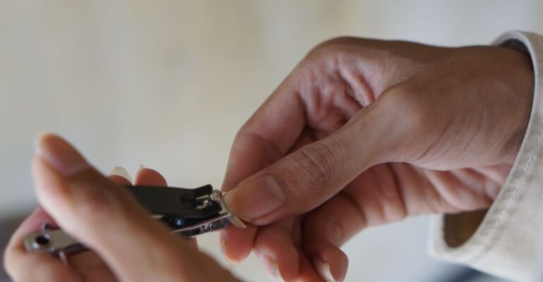 Close-up of hands using nail clipper for personal grooming