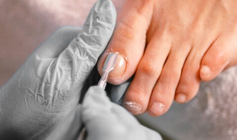 Beautician applying nail polish during professional pedicure session at salon spa