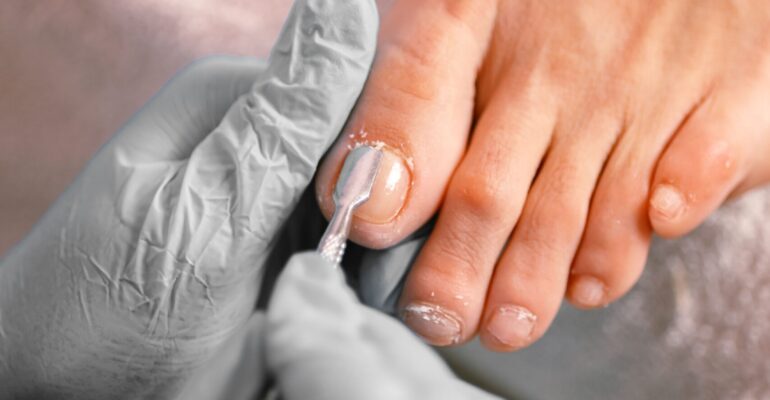 Beautician applying nail polish during professional pedicure session at salon spa