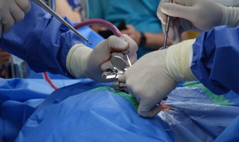 Surgeons in sterile gloves performing precise spinal stabilization operation in modern operating room with advanced instruments