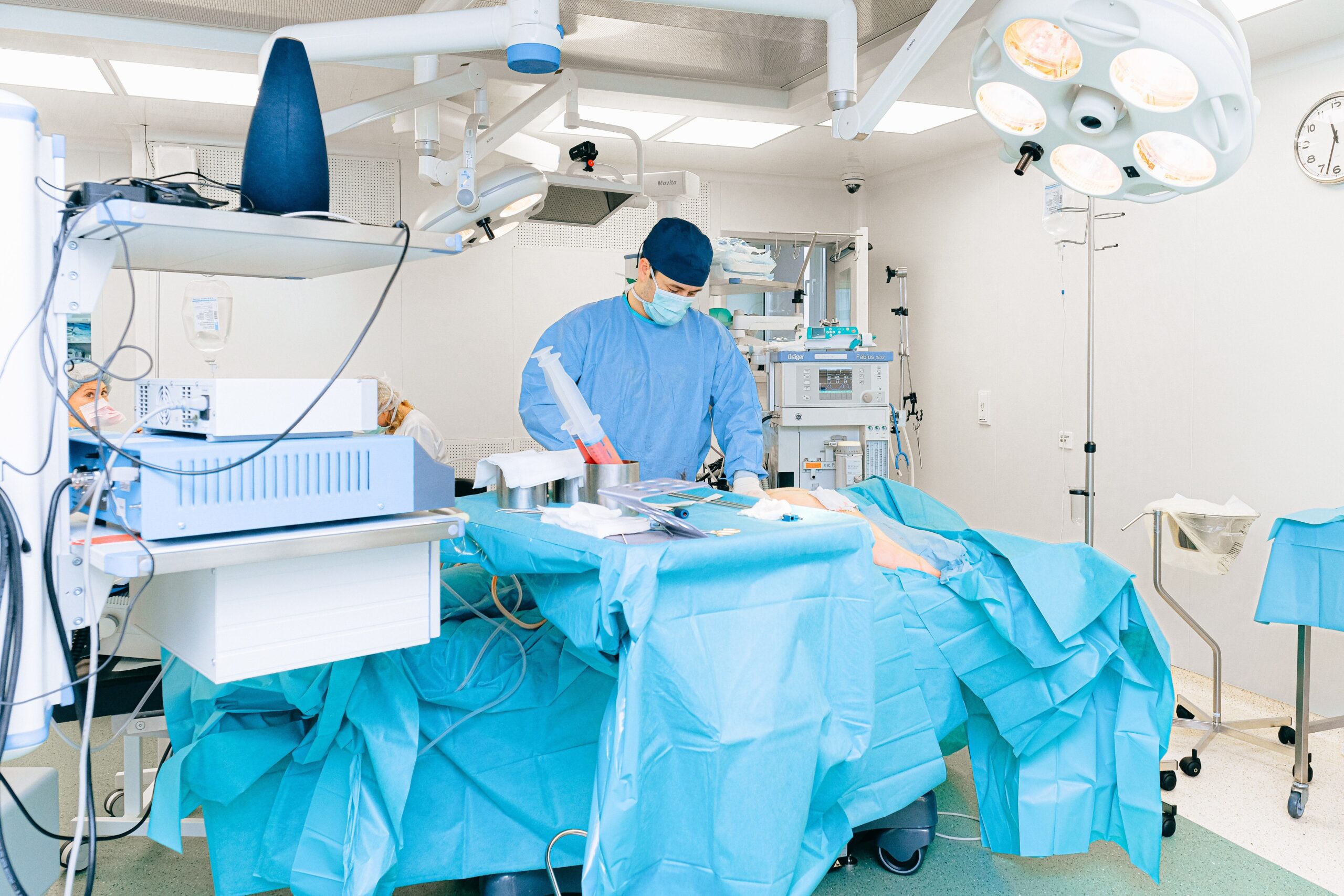 Spine surgeon in operating room gown and mask prepared for spinal stabilization procedure with surgical team