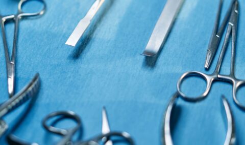 Stainless steel surgical instruments on blue background showing high quality metal finish used in orthopedic surgery