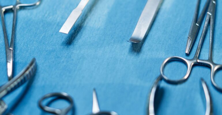 Stainless steel surgical instruments on blue background showing high quality metal finish used in orthopedic surgery