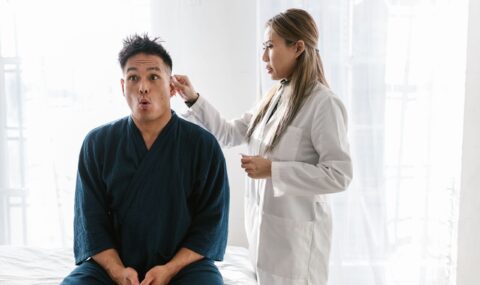 Physician conducting thorough ear examination using otoscope on patient in medical office