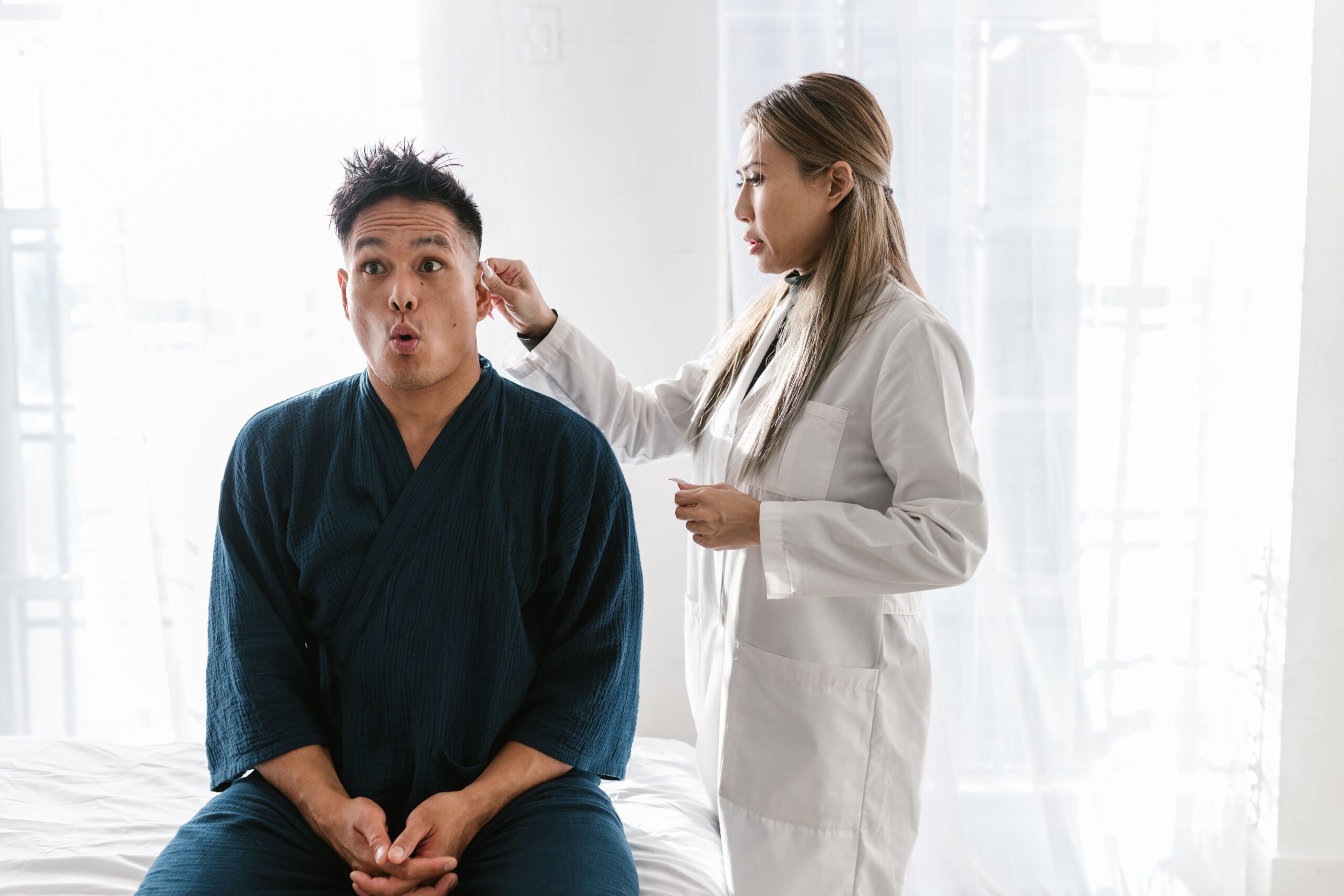Doctor conducting ear examination with otoscope in clinic