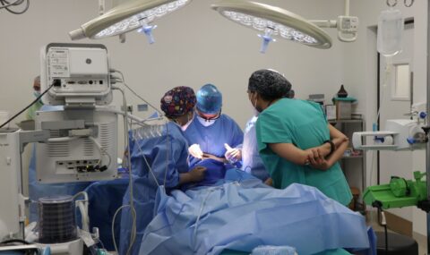 Team of surgeons operating together in a well-equipped modern surgical operating room with advanced medical technology and bright surgical lights