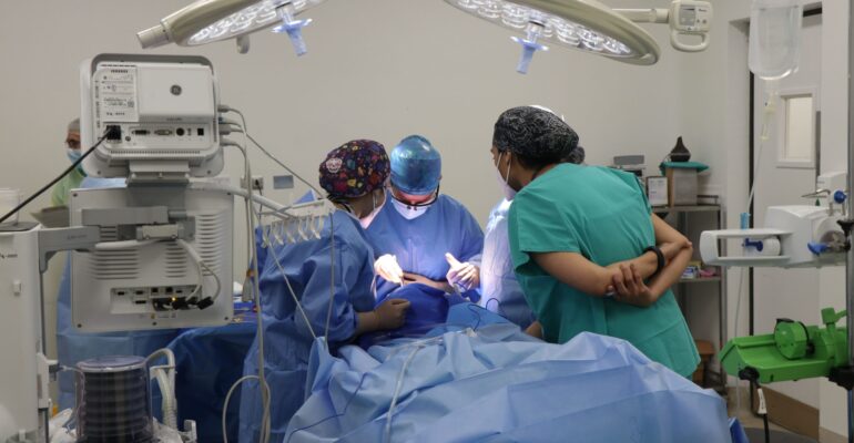 Team of surgeons operating together in a well-equipped modern surgical operating room with advanced medical technology and bright surgical lights